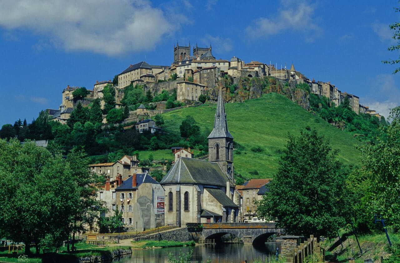 Ein charmantes Dorf mit Kirche und Brücke, ideal für geführte Motorradtouren in einer malerischen, historischen Umgebung.